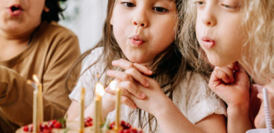 girls blowing out candles on a cake